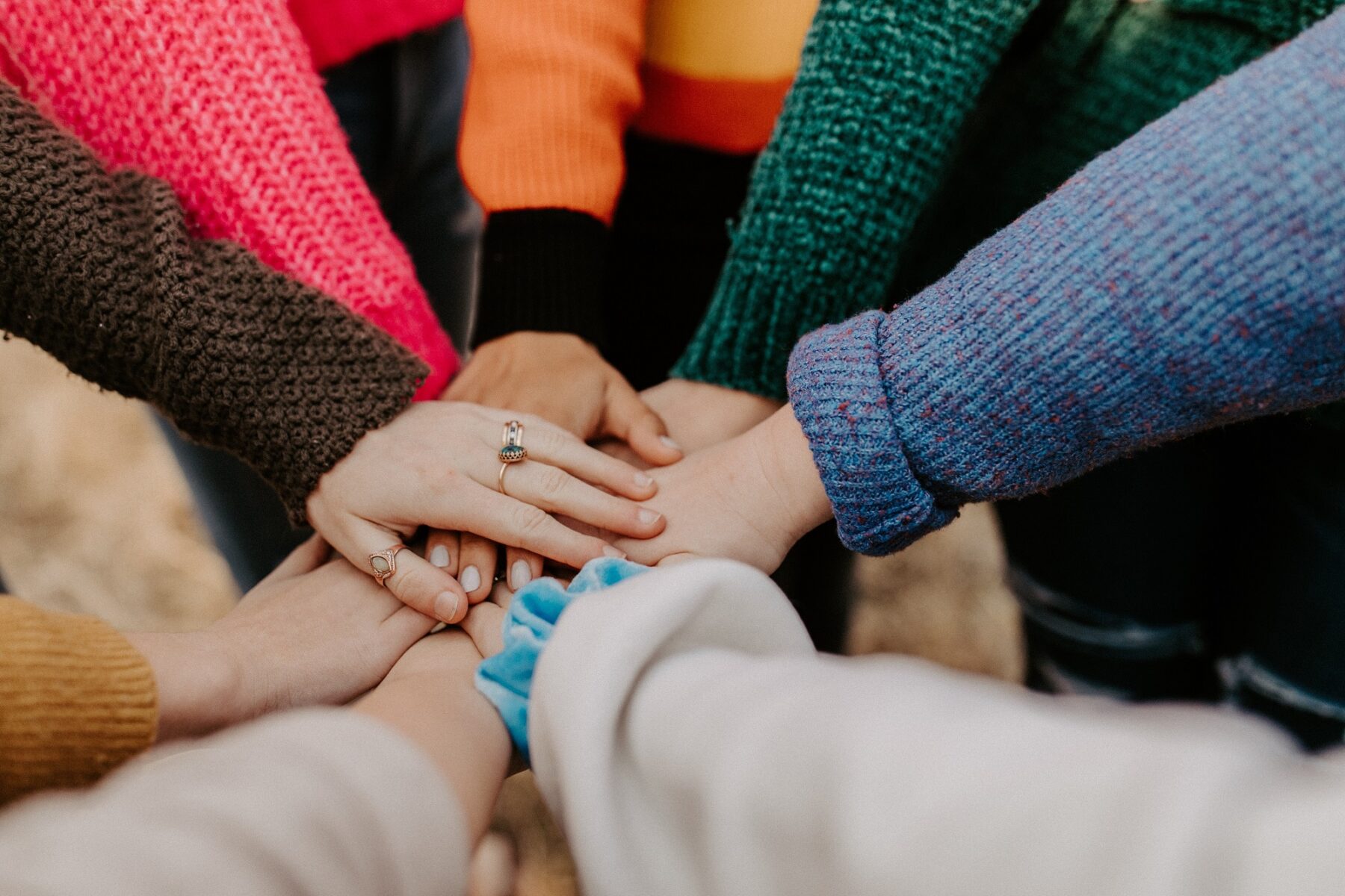 group of people with one hand stacked on top of each other from diverse backgrounds